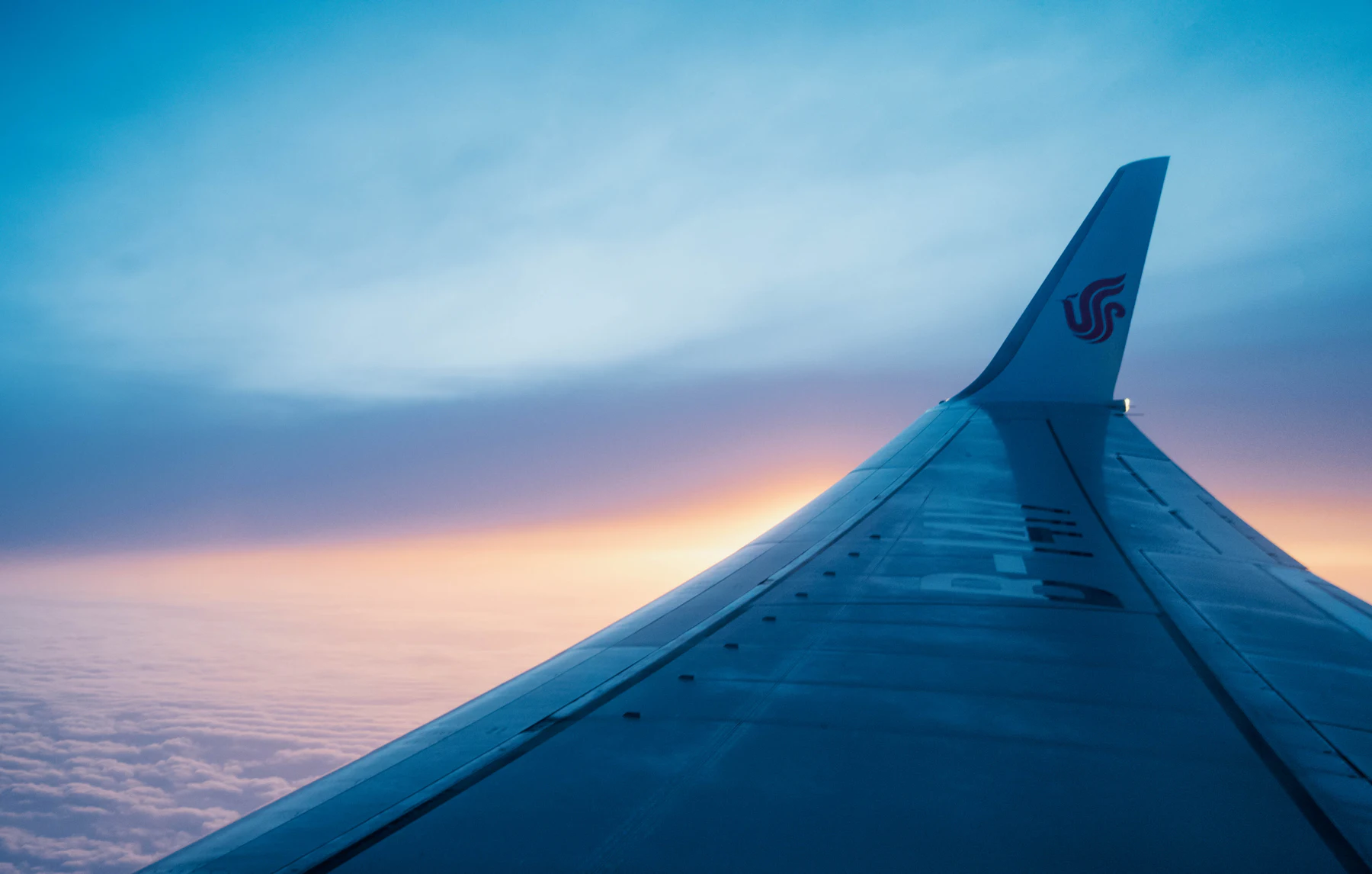 Flugzeugtragfläche über den Wolken bei Sonnenuntergang